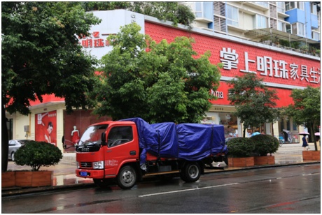 天在下雨，他们的红色小货车上，家具货品用防雨布严严实实盖着。