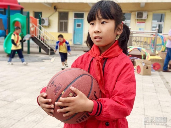 学校没有篮球架，但孩子们拿到篮球仍然很开心，图为小朋友抱着篮球爱不释手