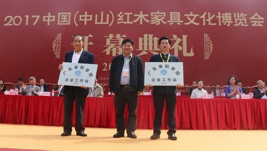 今年三月的中山红博会开幕式上，东成红木获得“广东省科学院企业工作站”授牌，董事长张锡复（右）上台领取牌匾